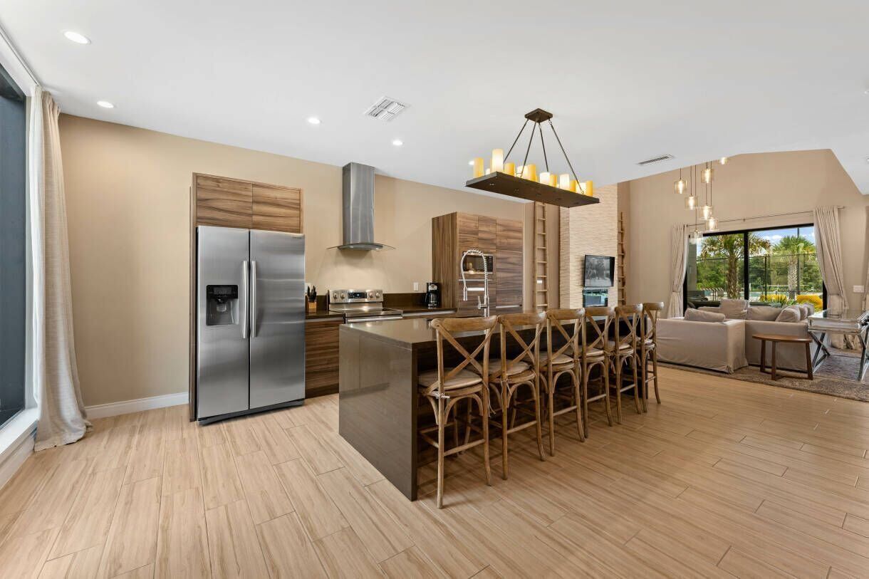 A modern kitchen with a central island, stainless steel appliances, and a dining area with wooden chairs.