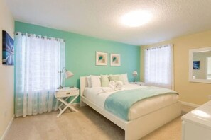 A bedroom with a bed, two bedside tables, a nightstand, and a window with curtains.