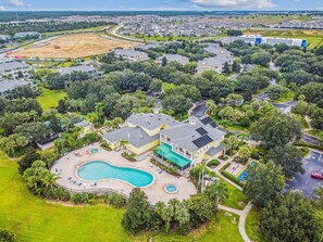 An aerial view of a residential area with houses, a large swimming pool, and a golf course. - 3BR Lakeside Apartment at Bahama Bay (Davenport)