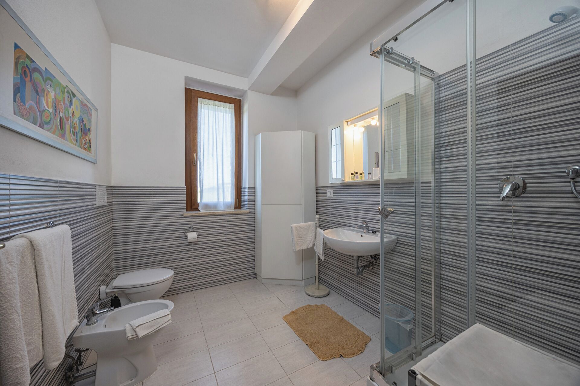 Ein Badezimmer mit zwei Toiletten, einem Waschbecken, einer Dusche und einem Fenster.