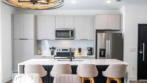 A modern kitchen with white cabinets, stainless steel appliances, and a central island with bar stools.
