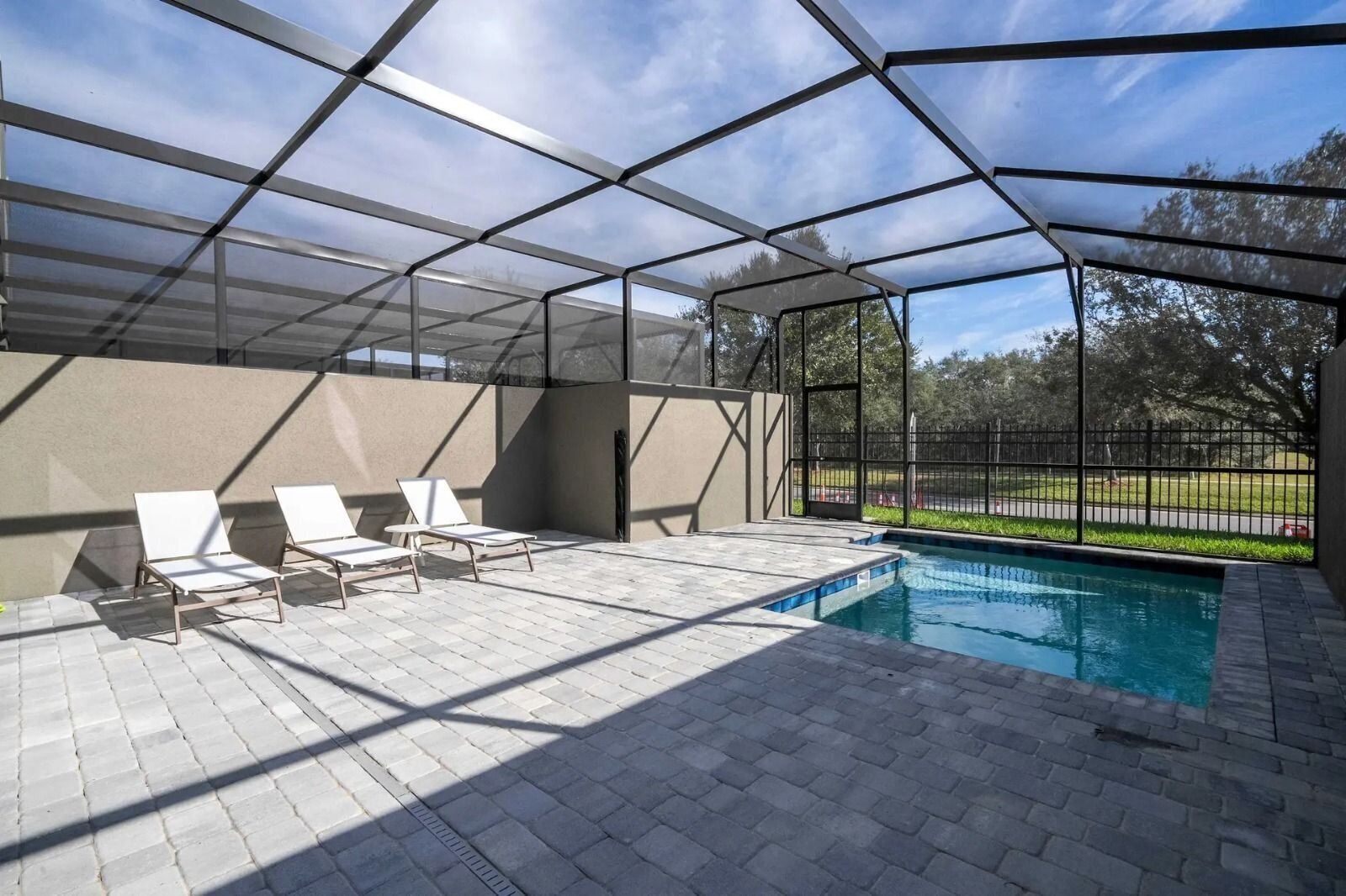 A covered outdoor swimming pool area with lounge chairs and a view of the surrounding landscape.