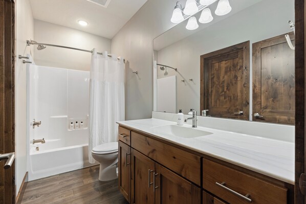 A modern bathroom with a bathtub, toilet, and vanity with a large mirror. - Resort Amenities the Heart of Crosslake|Beach|Swim (Crosslake)