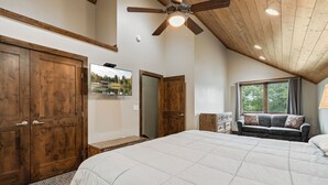A bedroom with a large bed, wooden wardrobe, ceiling fan, and a window with curtains. - Resort Amenities the Heart of Crosslake|Beach|Swim (Crosslake)