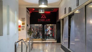 Un couloir avec un escalier, une enseigne « ZONEAIR Original Fitness » et un aménagement intérieur moderne.