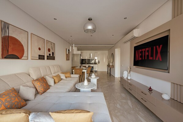 A modern living room with a large sofa, a TV, and artwork on the wall.