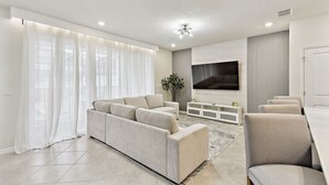 Una sala de estar moderna con sofá, sillones, televisor y comedor.