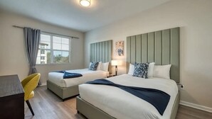Habitación de hotel con dos camas, un escritorio y una silla.