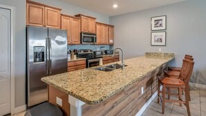 A kitchen with granite countertops, stainless steel appliances, wooden cabinets, a microwave, and a sink.