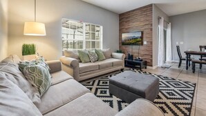 A modern living room with a sofa, ottoman, and a patterned rug.