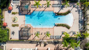 An aerial view of a hotel with a central swimming pool, lounge areas, and palm trees. - Private Pool Home in Bella Vida Resort (Kissimmee)