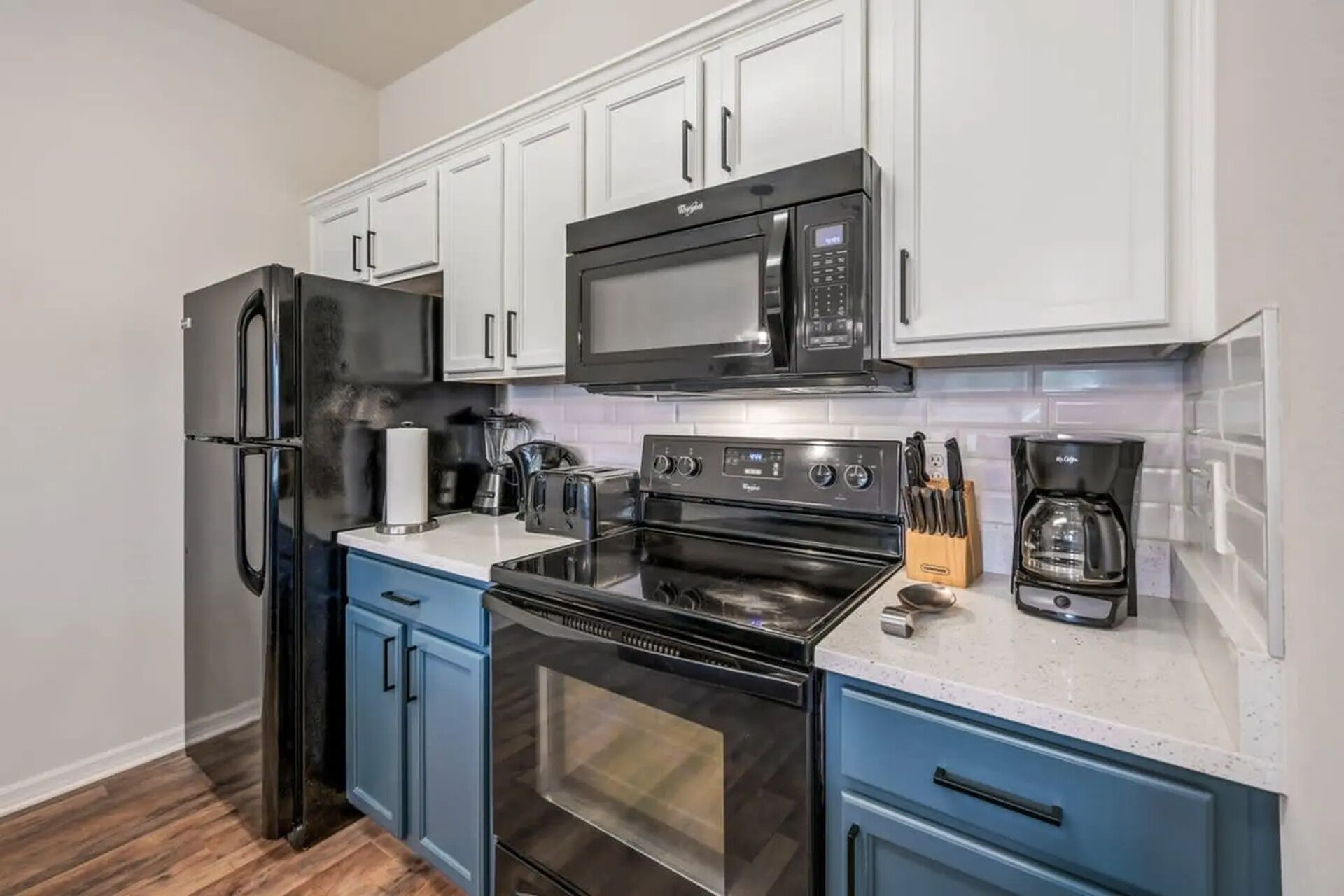 A compact kitchen with a refrigerator, microwave, stove, and oven.