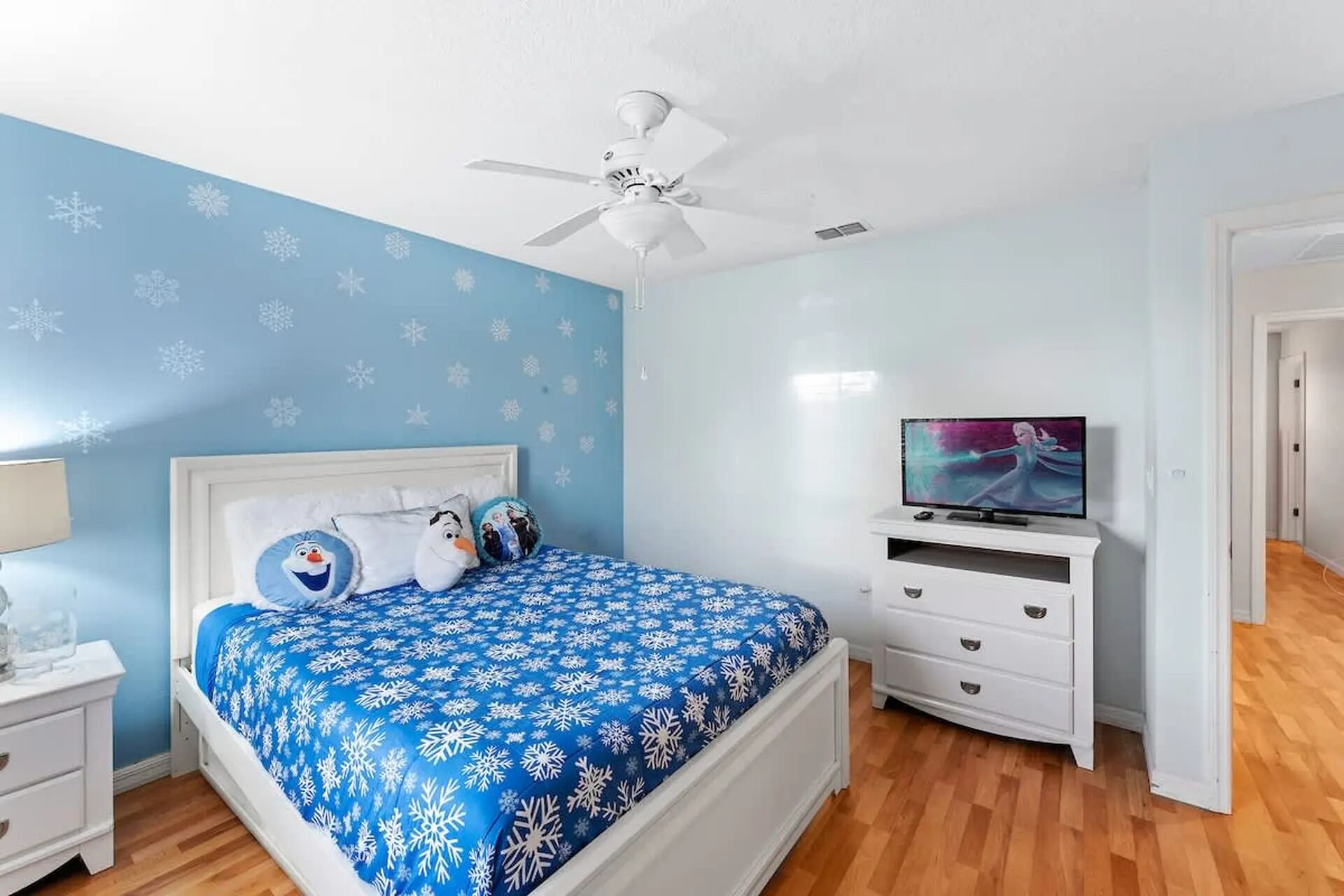 A bedroom with a bed, a TV, a nightstand, and a dresser.