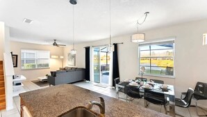 A modern kitchen with granite countertops, a double sink, and a dining area with a table and chairs. - Themed House with Pool and Comfort (Kissimmee)