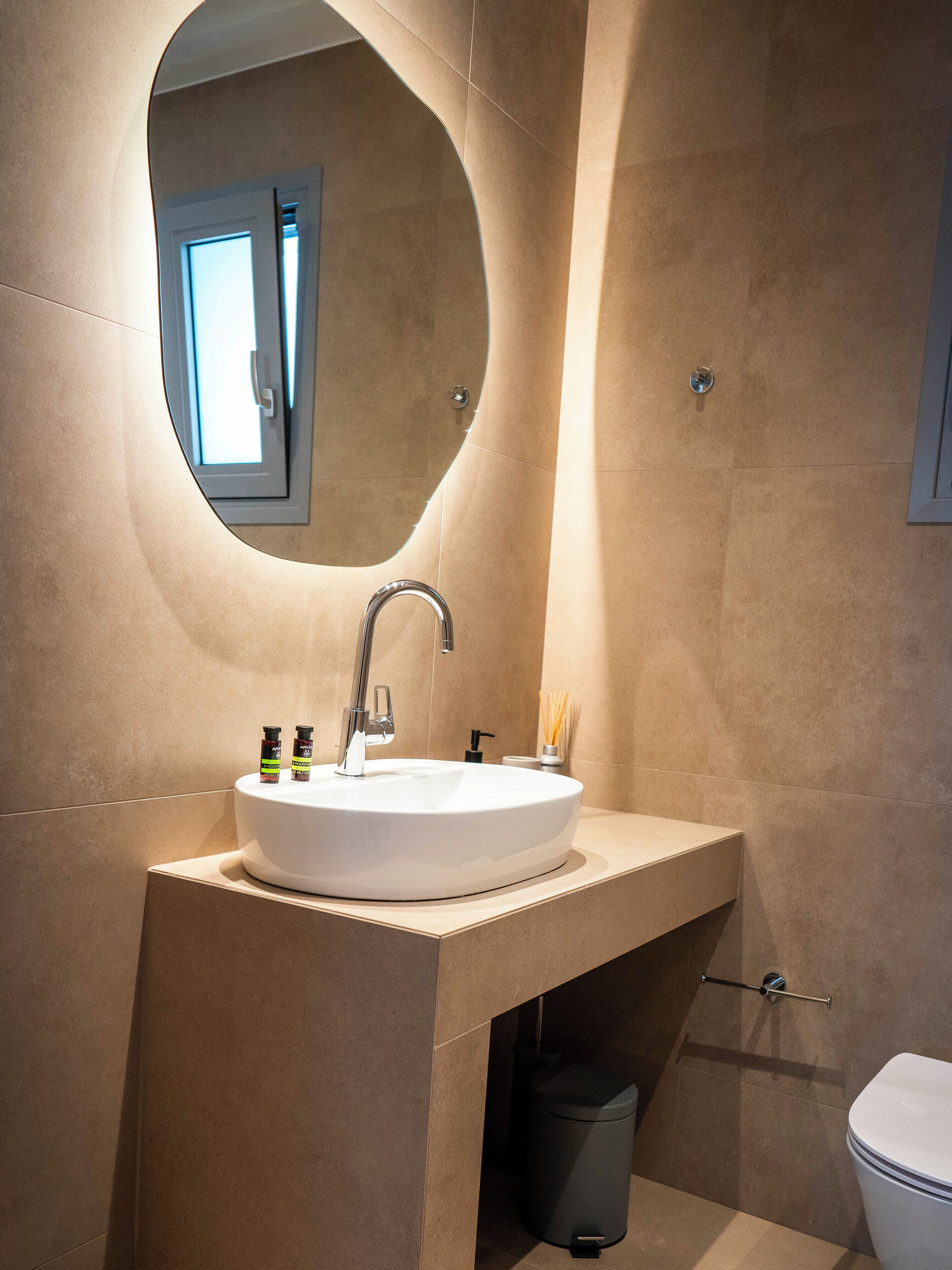 A modern bathroom with a round sink, a mirror, and a toilet.