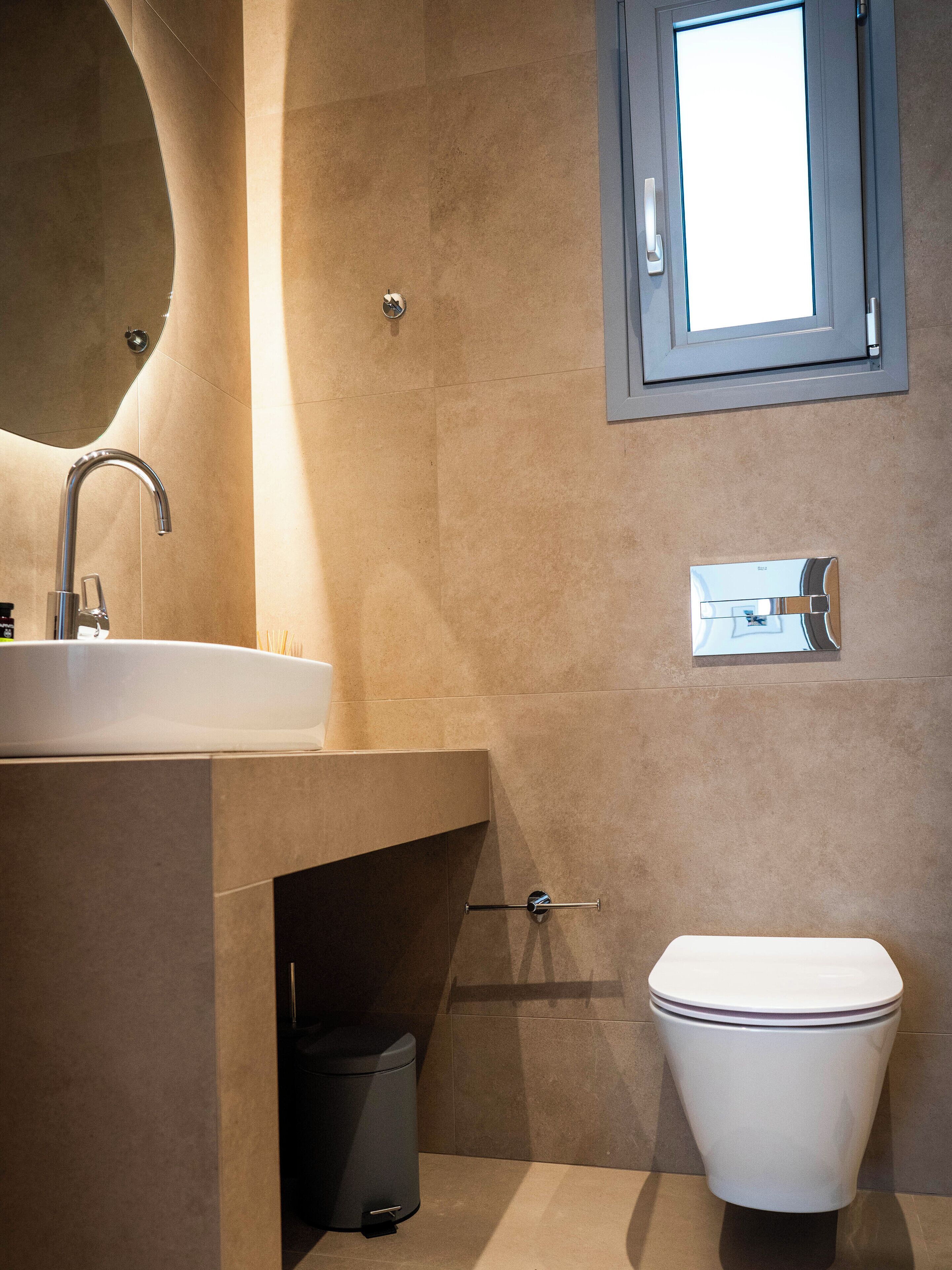 A modern bathroom with a sink, toilet, and a mirror.