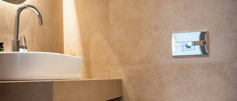 A modern bathroom with a sink, toilet, and a mirror.
