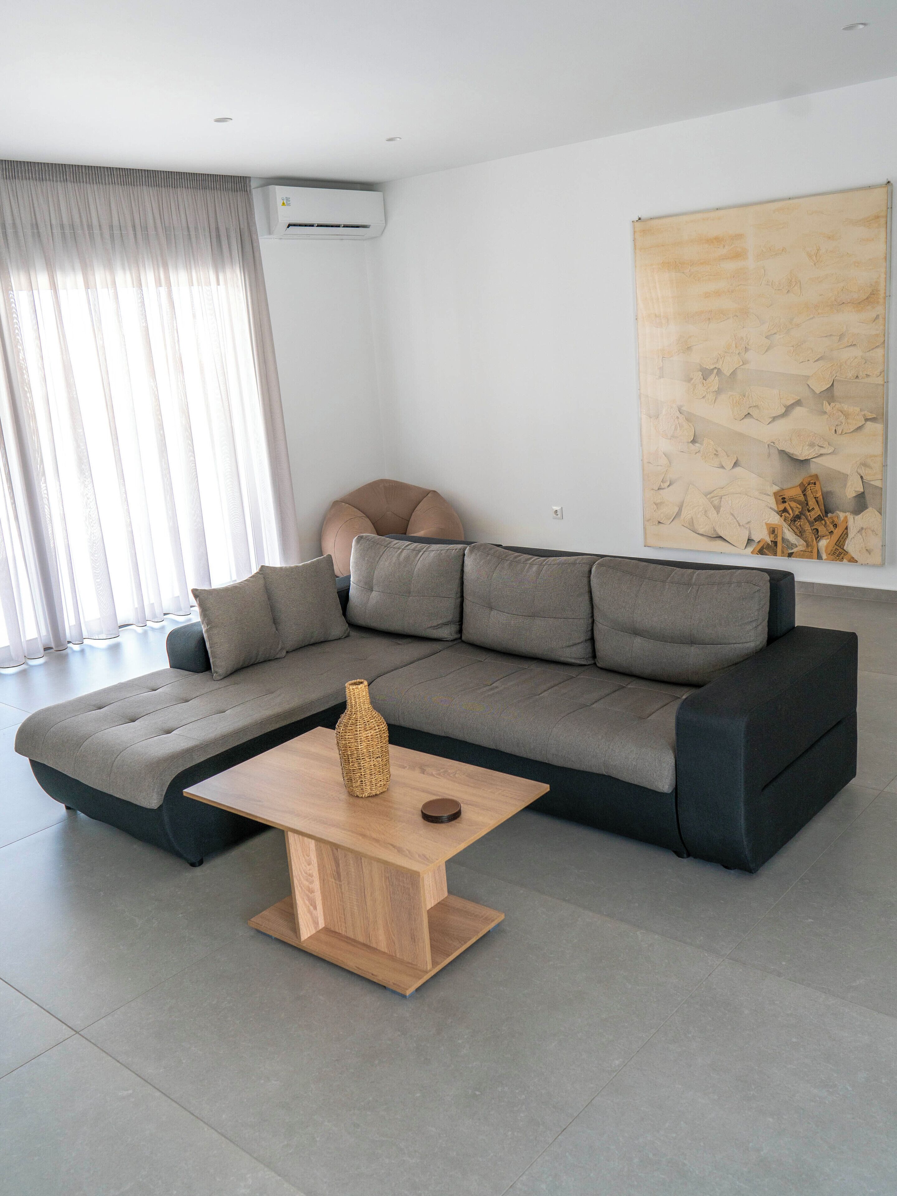 A modern living room with a sectional sofa, a wooden coffee table, and a large abstract painting on the wall.