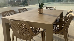 A rooftop terrace with a table and chairs, a potted orchid, and a city view. - WHITE LUXURY APARTMENT (Trikala)