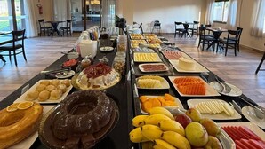 A buffet with various food items and a spacious dining area with tables and chairs.