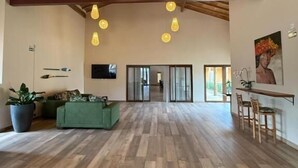 A spacious room with a high ceiling, wooden beams, and hanging pendant lights.