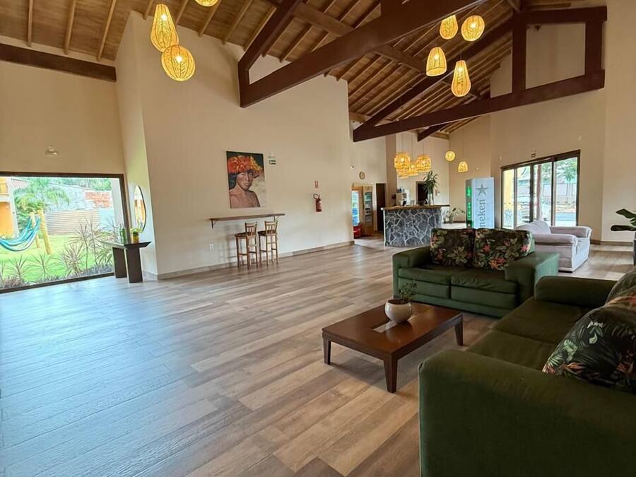 Un salón amplio con suelo de madera, un sofá verde, una mesa de centro y lámparas colgantes.