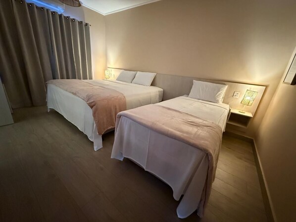 A hotel room with two beds, a ceiling fan, and a bedside table with a lamp.