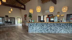 A reception area with a stone counter, wooden ceiling beams, and hanging pendant lights.