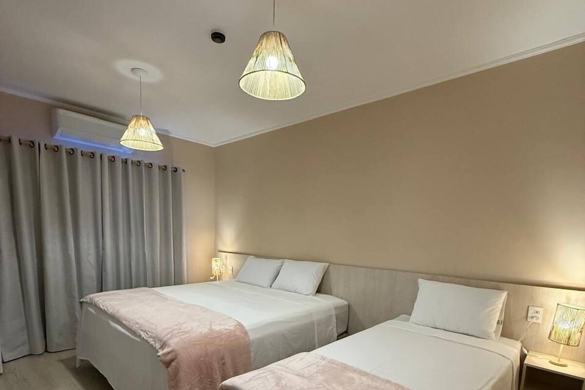 Une chambre d’hôtel avec deux lits, une table de chevet, une lampe et un luminaire au plafond.