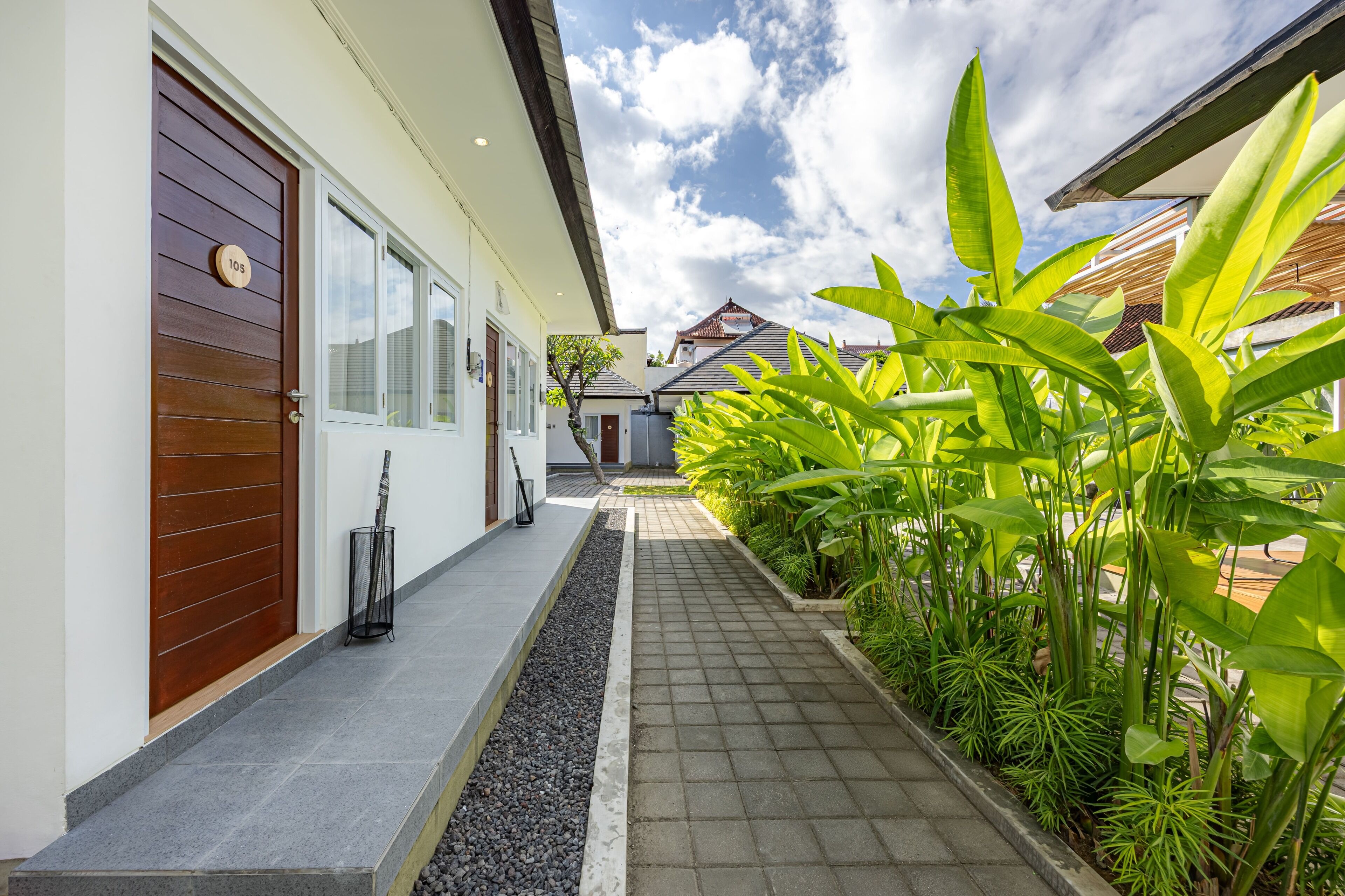 A pathway leading to a house with a number plaque, a door, and a window.