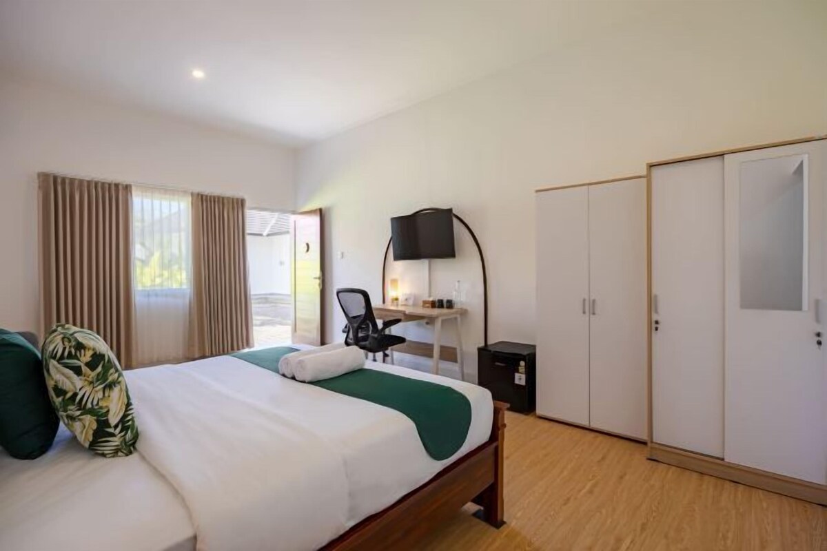 Una habitación de hotel con cama, escritorio, silla, televisor y armario.