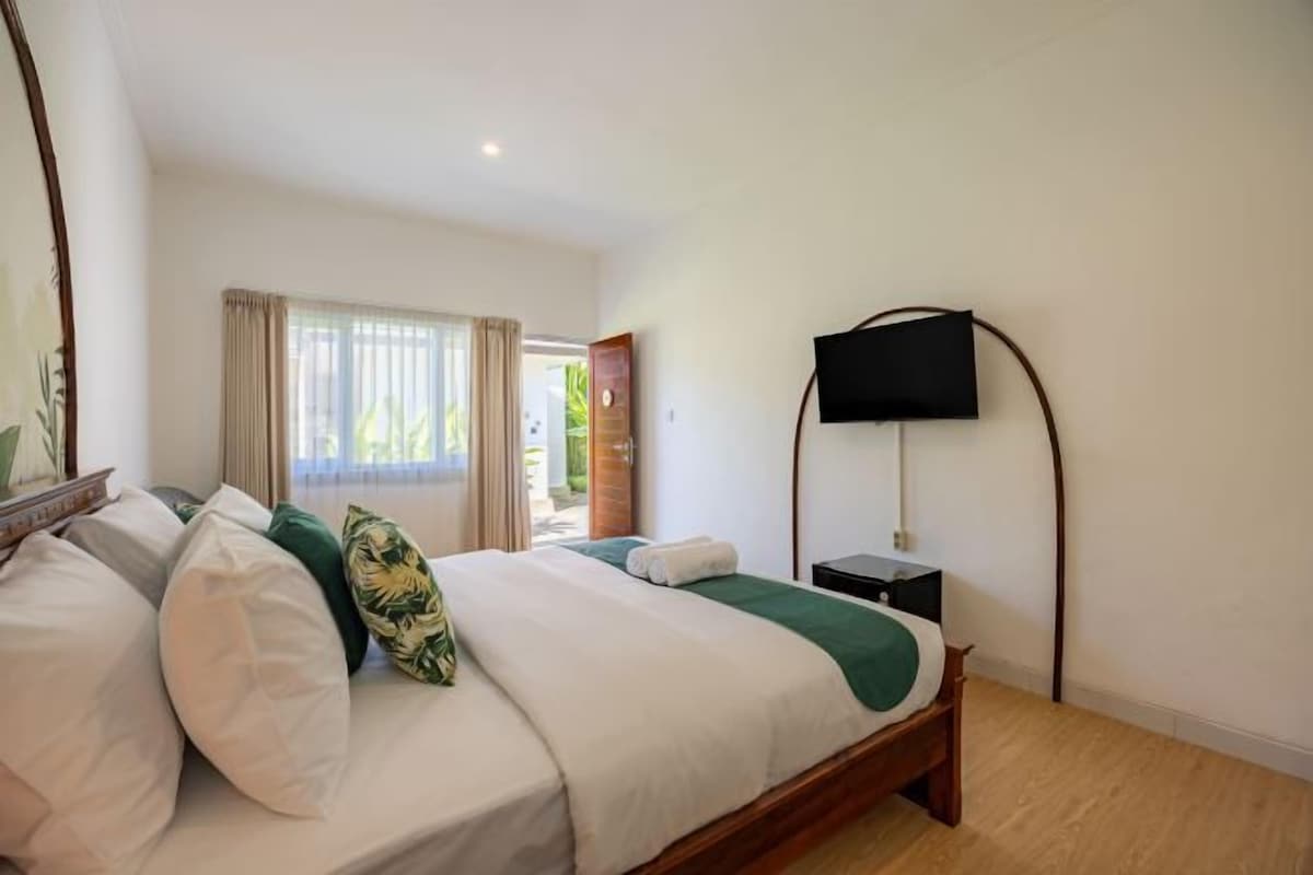 Ein Hotelzimmer mit einem Bett, einem an der Wand befestigten Fernseher und Blick ins Freie.