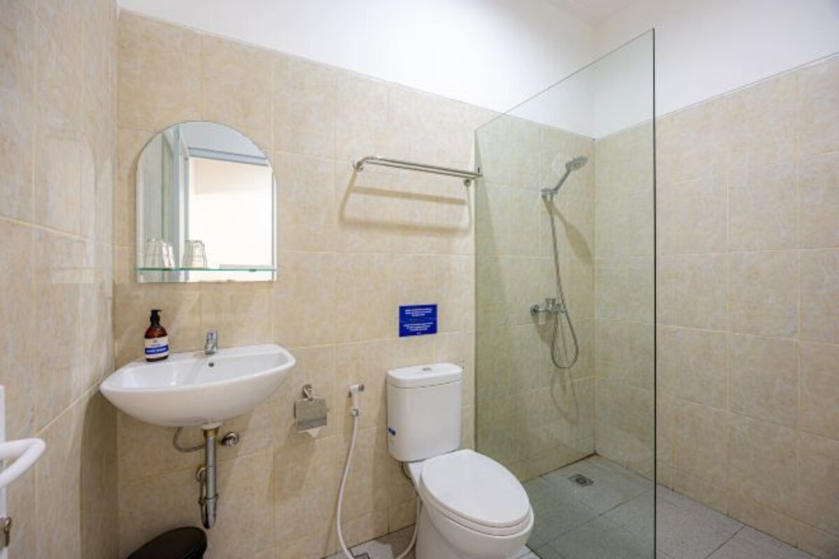 Un bagno completo di lavandino, specchio, WC e cabina doccia in vetro.