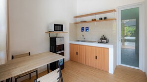 A compact kitchen with a microwave, water dispenser, and a sink. There are wooden cabinets and a small countertop. - Cove Dahayu Sanctuary (Denpasar)