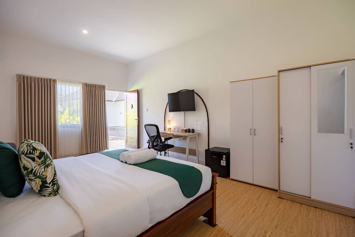 Una habitación de hotel con cama, escritorio, silla, armario y televisor.