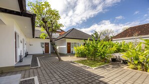 A courtyard with a tiled floor, a tree, and a building with a tiled roof. - Cove Dahayu Sanctuary (Denpasar)