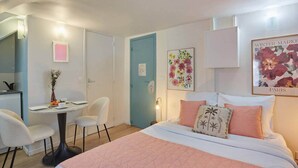 A bedroom with a bed, a desk, chairs, and a door. - Lovely Studio Place Vendome Opera (Paris)