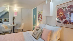 A bedroom with a bed, a desk, chairs, and a staircase. - Lovely Studio Place Vendome Opera (Paris)