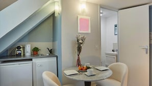 A compact kitchen with a sink, a kettle, and a coffee maker. There's a small dining table with chairs and a vase with flowers. - Lovely Studio Place Vendome Opera (Paris)