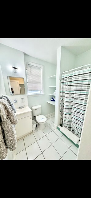 Een badkamer met toilet, wastafel, spiegel en douchegordijn.