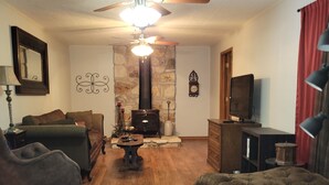 Una sala de estar acogedora con chimenea, televisor y ventilador de techo.
