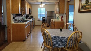 Una cocina con armarios de madera, una mesa de comedor con mantel a cuadros y un ventilador de techo.