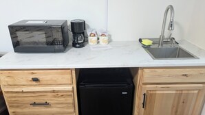 A compact kitchen with a microwave, coffee maker, and small refrigerator. - South of the Border Lodging (Canaan)
