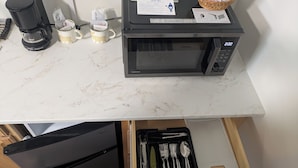 A kitchen area with a microwave, coffee maker, and utensils in a drawer. - South of the Border Lodging (Canaan)