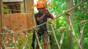 A person navigating a rope course in a forested area.