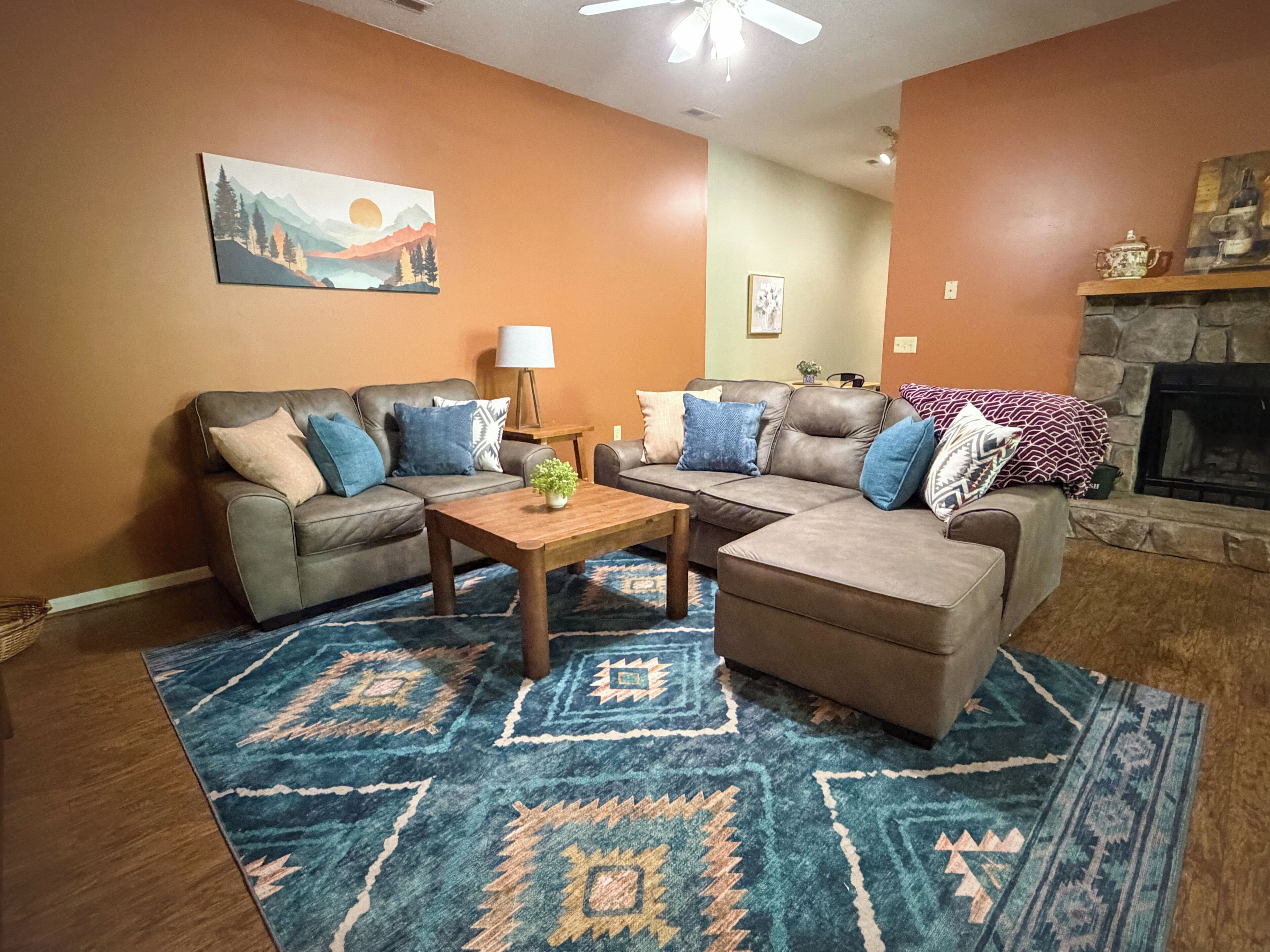 A living room with two sofas, a coffee table, a patterned rug, a fireplace, and a painting on the wall.