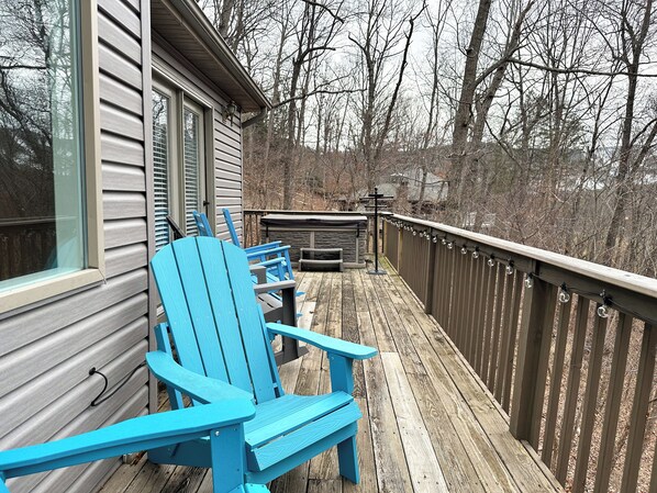 A wooden deck with two blue Adirondack chairs, a stone fireplace, and a wooden railing. - Spacious Mtn Chalet - Hot Tub & Minutes from Slopes, Trails, & Wineries (McGaheysville)