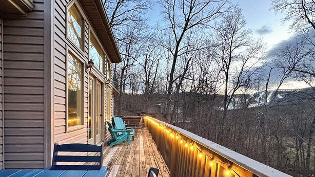 A wooden deck with outdoor seating, a railing, and string lights.