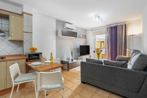 A modern living space with a kitchen, dining area, and a gray sofa.