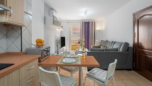 A compact living space with a kitchenette, dining area, and a sofa.